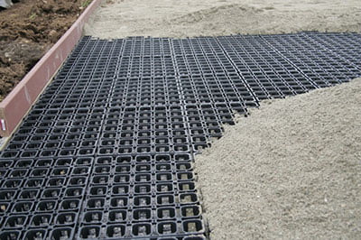 A permeable arena base partially covered with sand