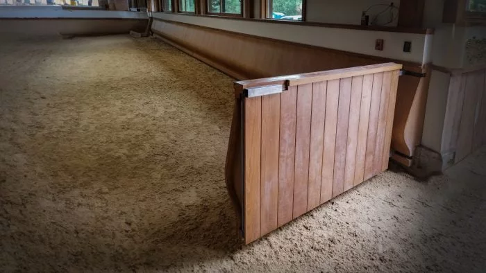 A swinging gate panel in an indoor arena with the curved arena kick wall