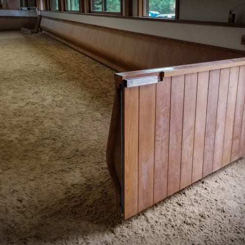 A swinging gate panel in an indoor arena with the curved arena kick wall