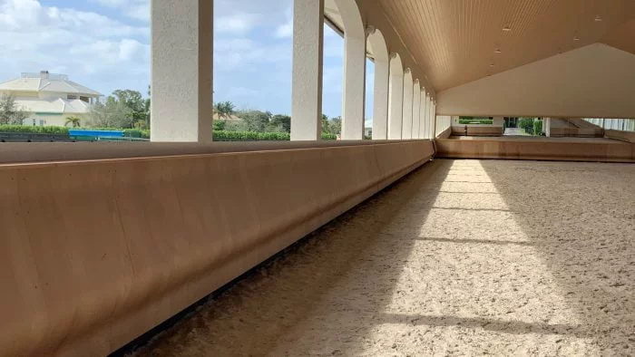 The long side of a covered arena with arched pillars over the curved kickwall