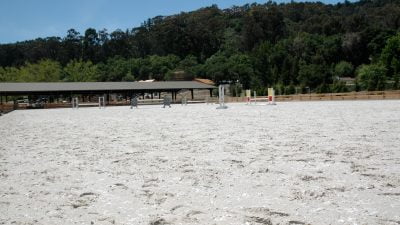 A wide angle photo of a riding arena with geotextile footing