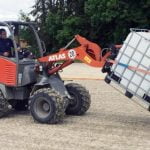 A tractor spreads Hydro SandBinder in a sand arena