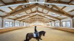 A horse and dressage rider ride by in a blur in an indoor arena