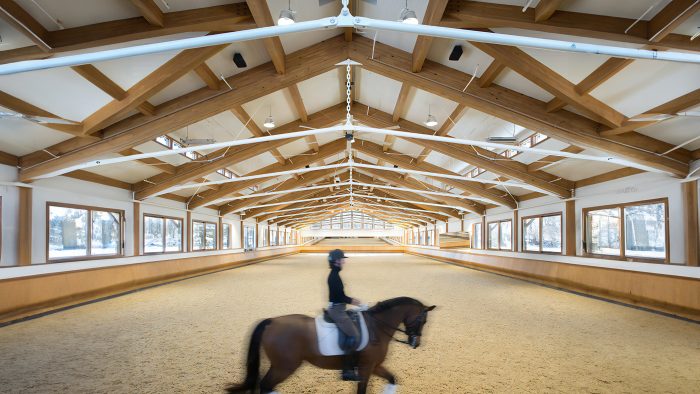 A horse and dressage rider ride by in a blur in an indoor arena