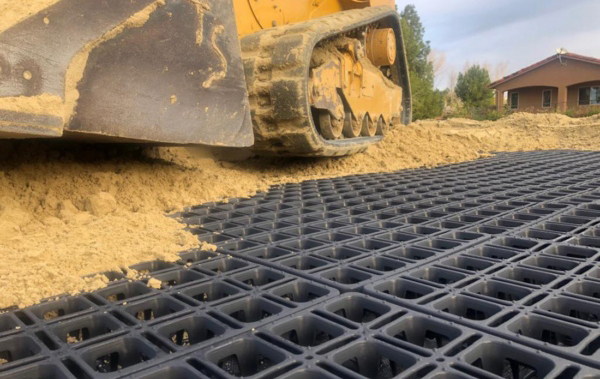 A closeup of HIT draingrids with heavy machinery rolling sand over mats that have already been covered.