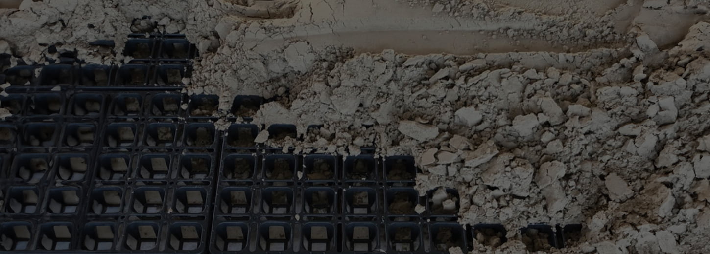 A cropped and darkened photo of HIT draingrids partially covered with sand.