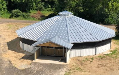 A custom covered horse walker with white paneling and a black roof