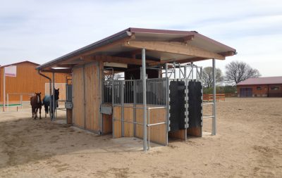 An automatic horse feeding station, accessed by transponder, with two horses in the background