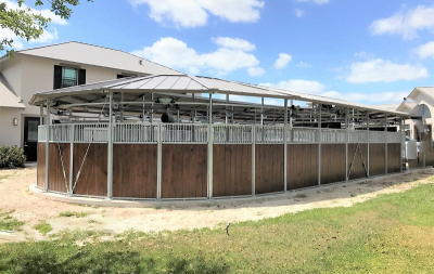 An oval horse walker taken on an angle, with a building in the background