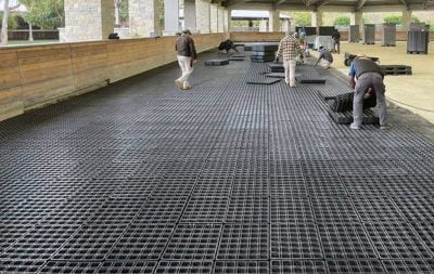 The covered arena at Delta Farms has a team of workers laying down HIT DrainGrids.