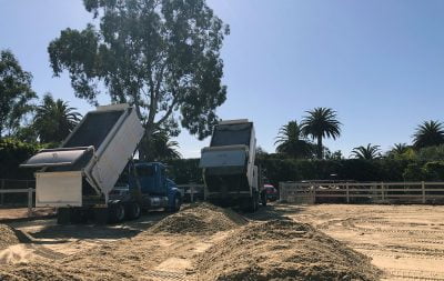 Construction trucks dump sand to be spread in the new outdoor arena at Hope Ranch.
