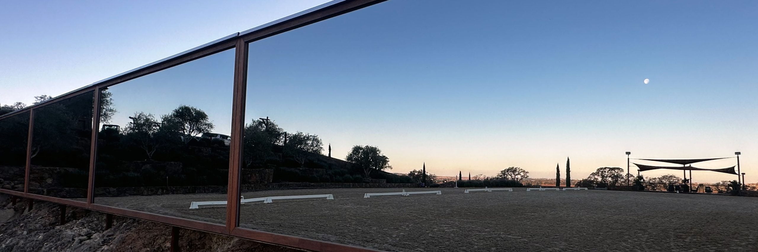 A row of arena mirrors reflecting the outdoor arena they are installed in at disk