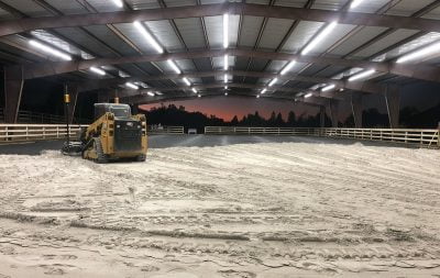 Heavy equipment spreads and evens sand in the North Peak Equestrian covered arena.