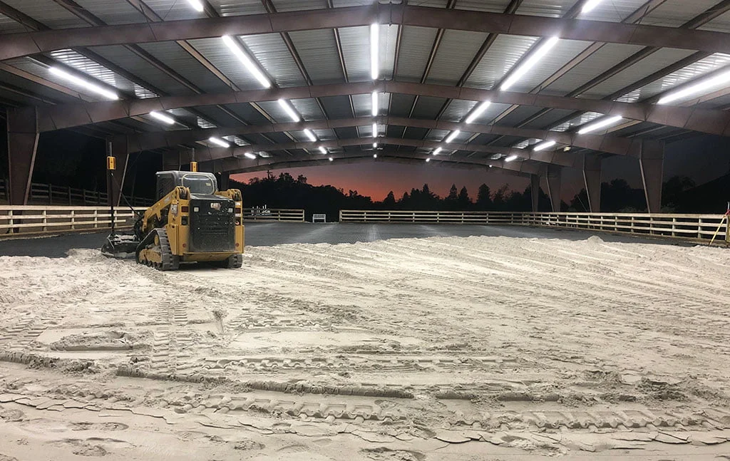 Heavy equipment spreads and evens sand in the North Peak Equestrian covered arena.
