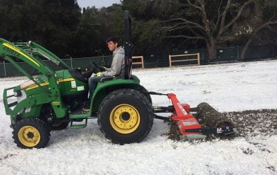 A tractor with arena groomer spreads FSGeoTEX.