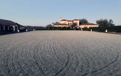 A nicely groomed outdoor arena with a large home in the background