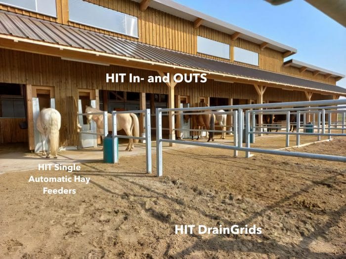 multiple horses stand in front for a barn labeled HIT in- and OUTS, with automatic hay feeders and HIT DrainGrides