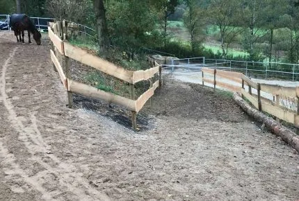 A fenced in mountain trail that has HIT Base Mats laid underneath. A dark horse is seen in the background.